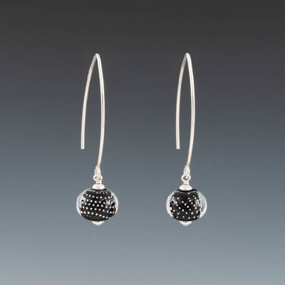 Black Sparkling Earrings (Long Ear Wires) by Becky Congdon are handmade black glass beads with silver dots encased in clear. The beads dangle from long contemporary simple ear wires. Each bead has small silver saucers on each side of it.