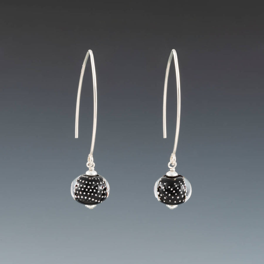 Black Sparkling Earrings (Long Ear Wires) by Becky Congdon are handmade black glass beads with silver dots encased in clear. The beads dangle from long contemporary simple ear wires. Each bead has small silver saucers on each side of it.