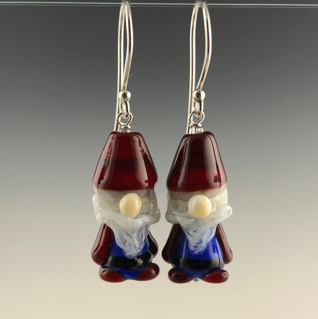 Gnome earrings are handmade glass beads each with red had, blue outfit, white beard and mustache, red boots, and big nose in glass. The are on simple ear wires. Zoom ready for the holidays! (front view)