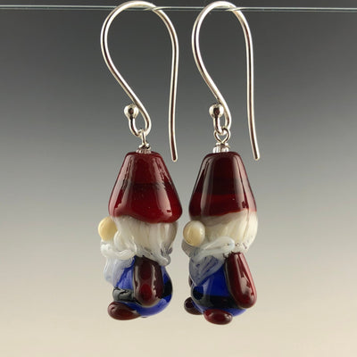 Gnome or Tomte glass beads with red pointed hats, bublous noses, blue outfits, black belts, and red boots. The beads are on simple sterling silver ear wires with small ball at top. Ready for Christmas! (side view)