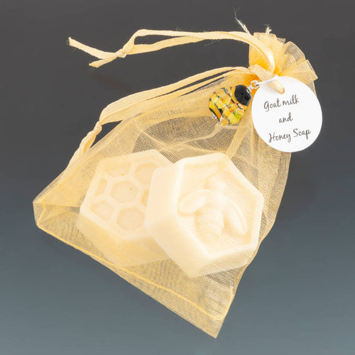 Two guest size goats milk and honey soap hexagonal in shape with bee and honeycomb embosed.  Soaps in gold organza bag with a handcrafted glass bee charm and circular tag attached at top with ribbon. All by Becky Congdon
