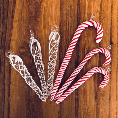 Three clear glass icicles with thin white wrap and three red and white candy canes displayed to show various sizes.
