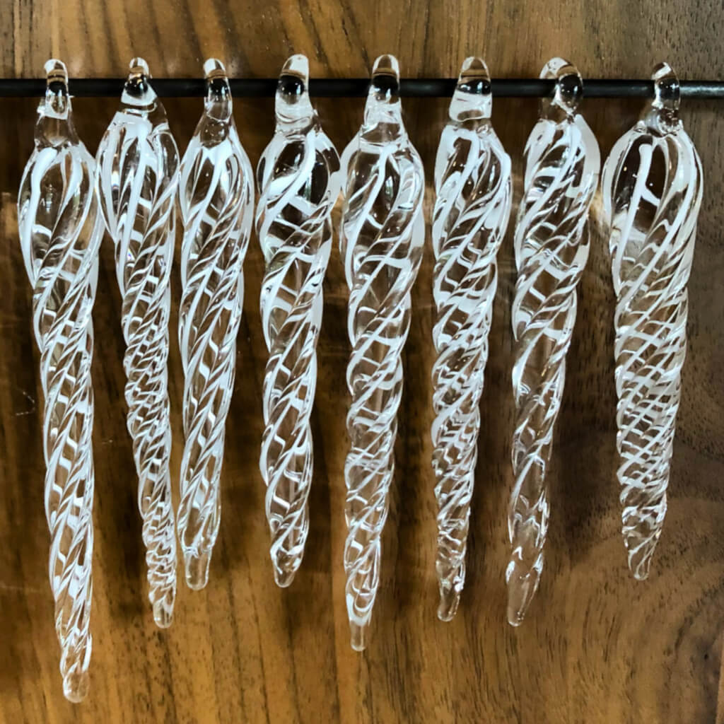 Ten clear glass with thin white twist taper from the top to tip are displayed.