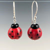 Handmade flameworked red and black ladybug glass beads hang from Bali silver ear wires by Becky Congdon