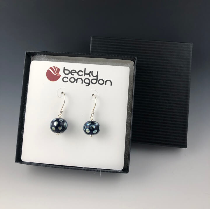 The handmade cobalt blue mirrored dot earrings are displayed on a earring card in a black pinstripe gift box.