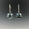 Handmade cobalt blue lentil-shaped beads with mirrored horizontal stripes dangle from silver leverbacks with small silver saucer beads on top and bottom of the glass beads.