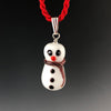 Holiday glass snowman pendant with a cross-eyed looking at his carrot colored nose, 3 black buttons, and white and red twisted scarf around neck and trails down his side. The snowman is on a sterling silver triangular bail on a twisted red satin cord necklace. Ready for Xmas!